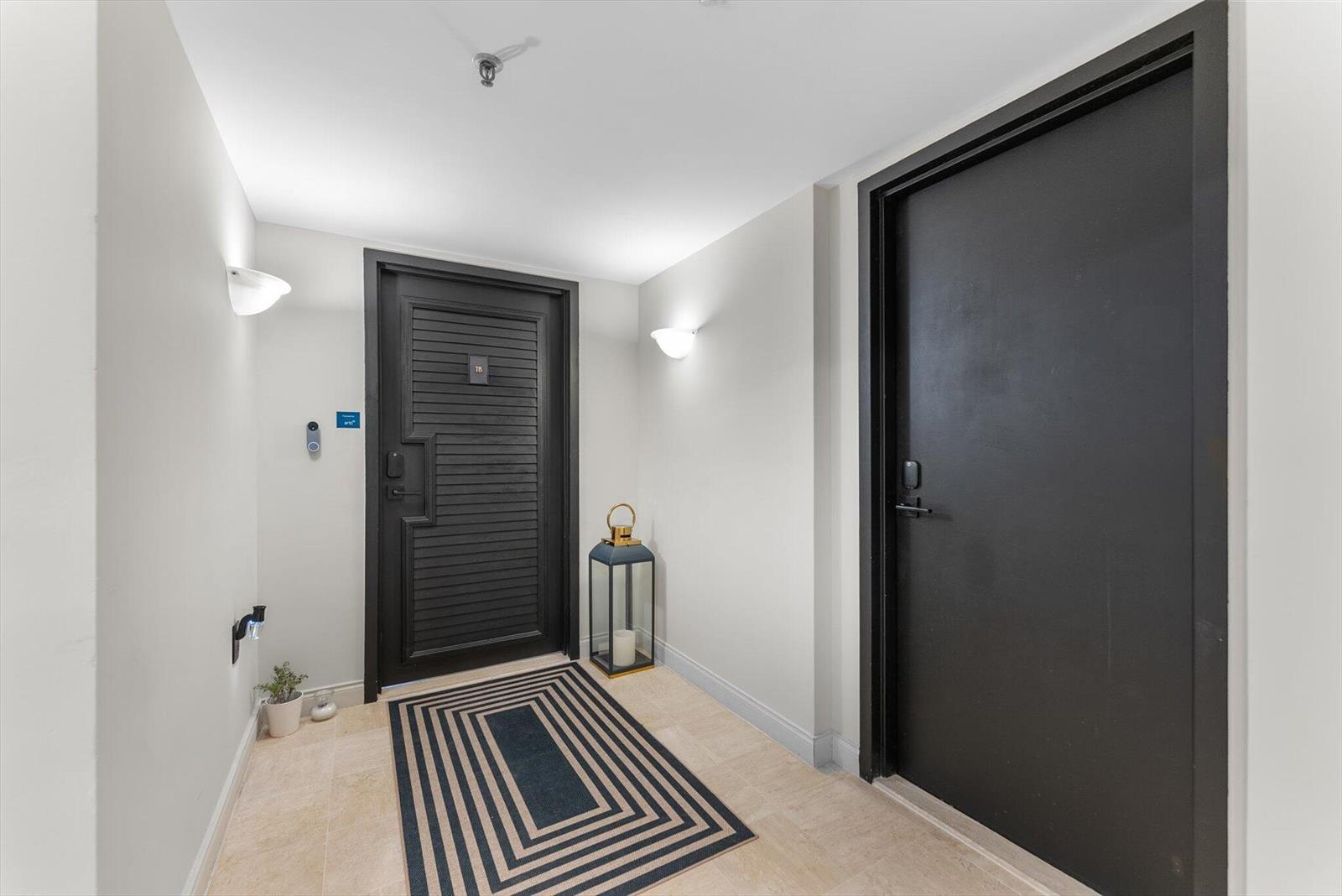 An entryway features two black doors, a striped rug, and wall-mounted sconces — 4605 S Ocean Boulevard # 7b, Highland Beach FL 33487, HIGHLAND BEACH, FL