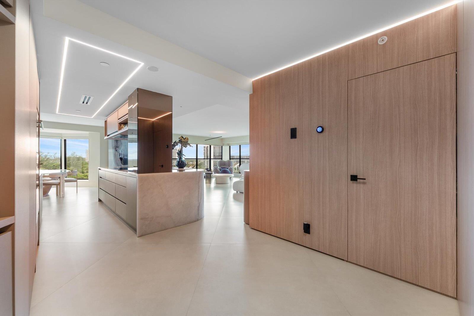 A modern kitchen and living area feature wood-paneled walls, marble counters, and floor-to-ceiling windows — 4605 S Ocean Boulevard # 7b, Highland Beach FL 33487, HIGHLAND BEACH, FL