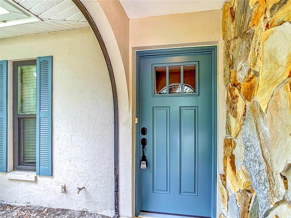 A blue front door with a glass insert sits under an arched entryway — 924 PHYLLIS TERRACE, PORT CHARLOTTE, FL
