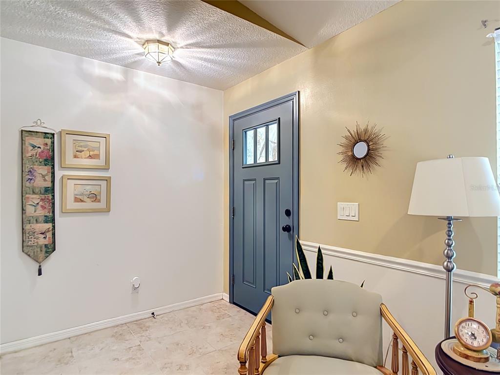 An entryway features a blue door, a light-colored armchair, and a lamp on a table — 924 PHYLLIS TERRACE, PORT CHARLOTTE, FL