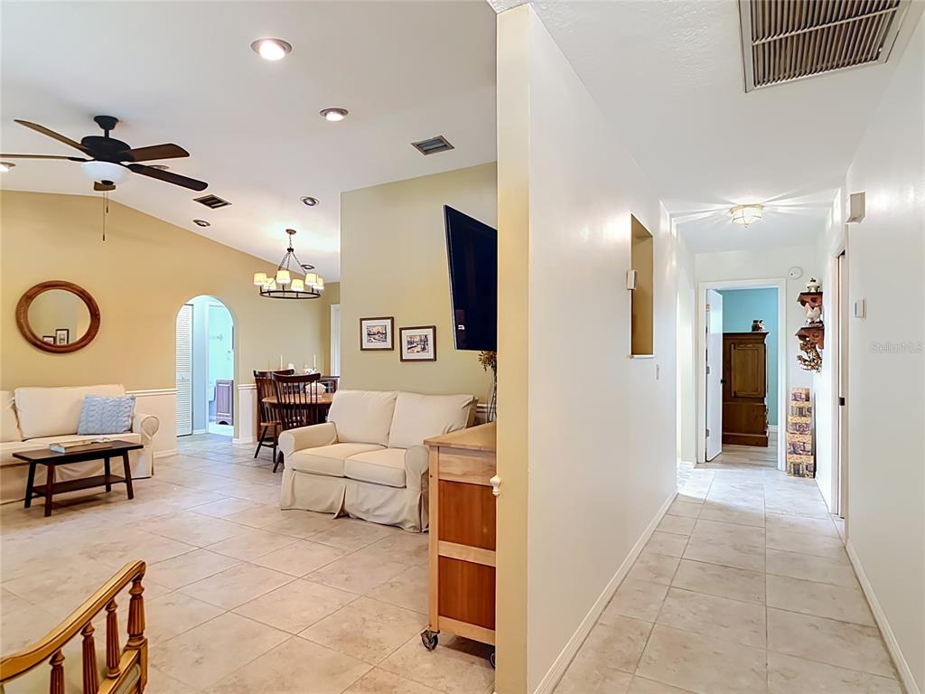 A living room and dining area with tile floors, a ceiling fan, and a hallway — 924 PHYLLIS TERRACE, PORT CHARLOTTE, FL