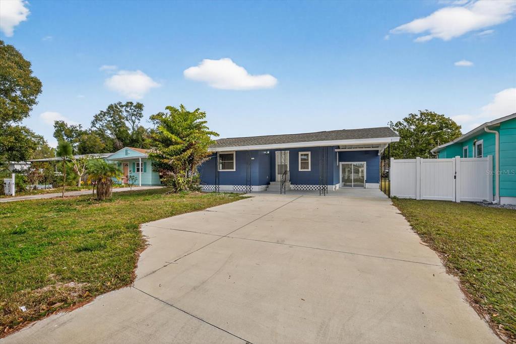 A blue single-story house with a concrete driveway and a white privacy fence — 5801 MAGNOLIA STREET N, ST PETERSBURG, FL