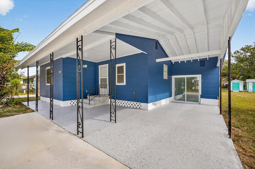 A blue house with a covered concrete patio, decorative metal columns, and a sliding glass door — 5801 MAGNOLIA STREET N, ST PETERSBURG, FL