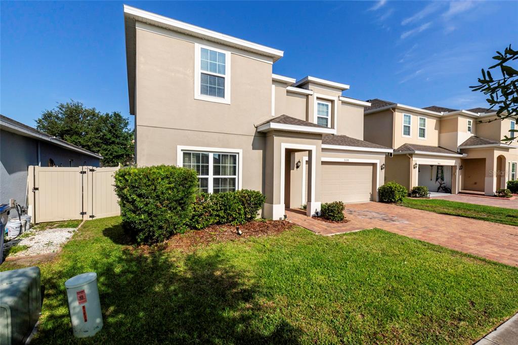A two-story suburban house with a beige stucco exterior, a brick driveway, and a lawn — 9399 VILLANOVA DRIVE, GROVELAND, FL