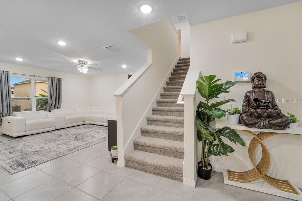 A living room with a white sectional sofa, carpeted stairs, and a Buddha statue — 35704 DOVELAND DRIVE, ZEPHYRHILLS, FL