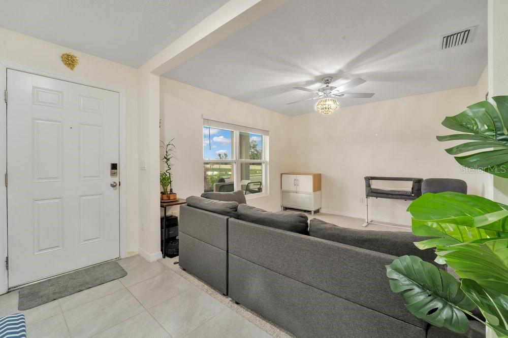 A living room with a gray sectional sofa, a ceiling fan, and a front door — 35704 DOVELAND DRIVE, ZEPHYRHILLS, FL