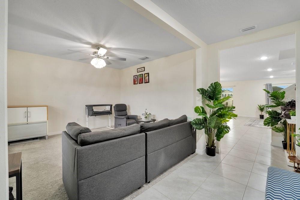 A living room with gray carpet, a gray sofa, and tile flooring in the entryway — 35704 DOVELAND DRIVE, ZEPHYRHILLS, FL
