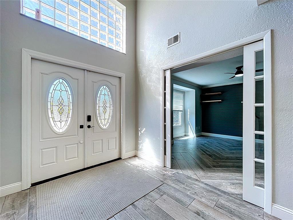 The exterior of a two-story house features a paved walkway, double doors, and glass blocks — 10655 LAKEVIEW DRIVE, NEW PORT RICHEY, FL