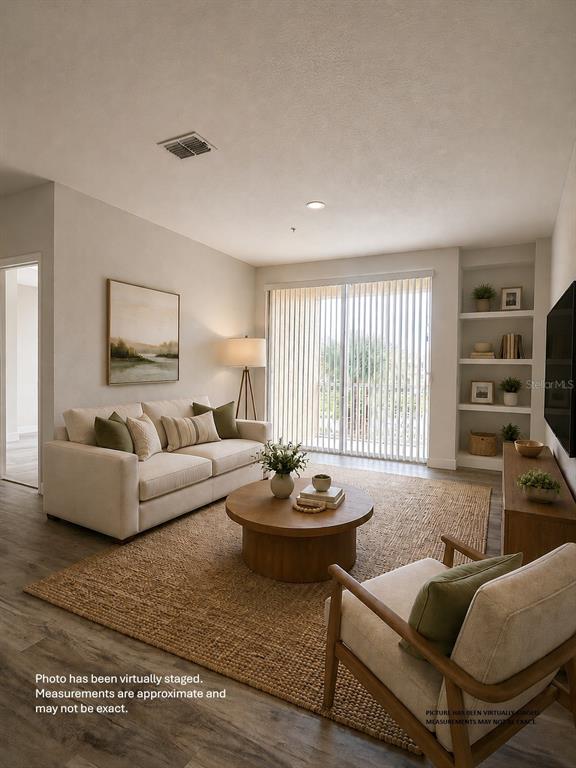 This is a virtually staged living room featuring a sofa, armchair, and built-in shelving — 1175 LAKE SHADOW CIRCLE UNIT 4202, MAITLAND, FL