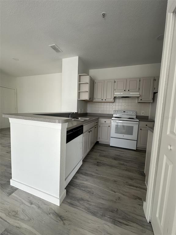 A kitchen features light-colored cabinets, white appliances, a breakfast bar, and wood-look flooring — 1175 LAKE SHADOW CIRCLE UNIT 4202, MAITLAND, FL