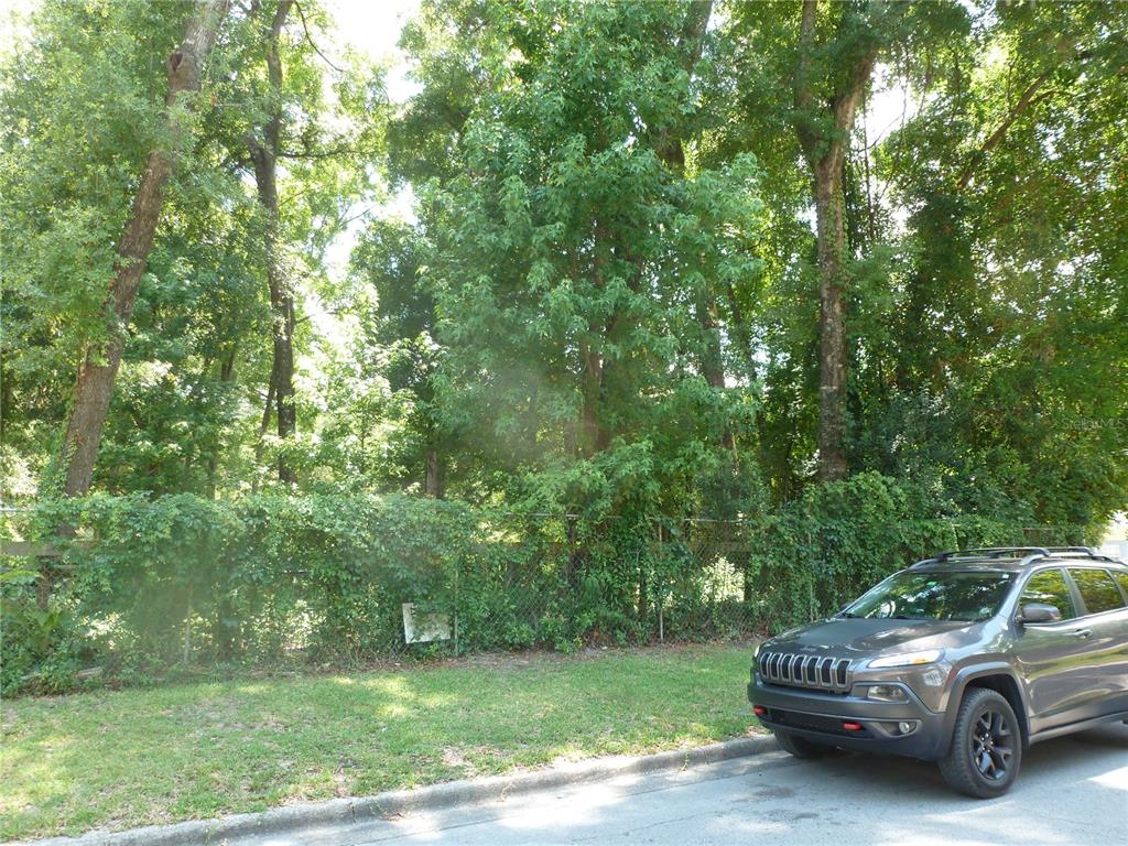A gray SUV is parked on a street in front of a chain-link fence — 1031 SW 62ND TERRACE, GAINESVILLE, FL