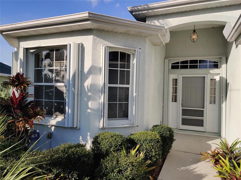 The exterior of a light-colored home features a front entrance and two arched windows — 4469 EDINBRIDGE CIRCLE UNIT 25, SARASOTA, FL