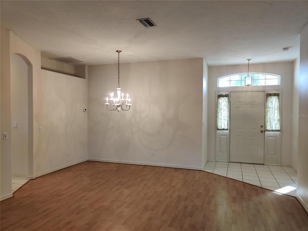 A dining area with wood-look flooring, a chandelier, and an adjacent tiled entryway — 4469 EDINBRIDGE CIRCLE UNIT 25, SARASOTA, FL