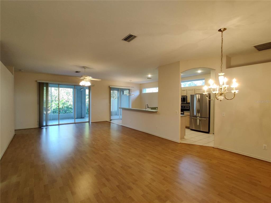 An open-concept living area features wood flooring, a breakfast bar, and a dining room chandelier — 4469 EDINBRIDGE CIRCLE UNIT 25, SARASOTA, FL