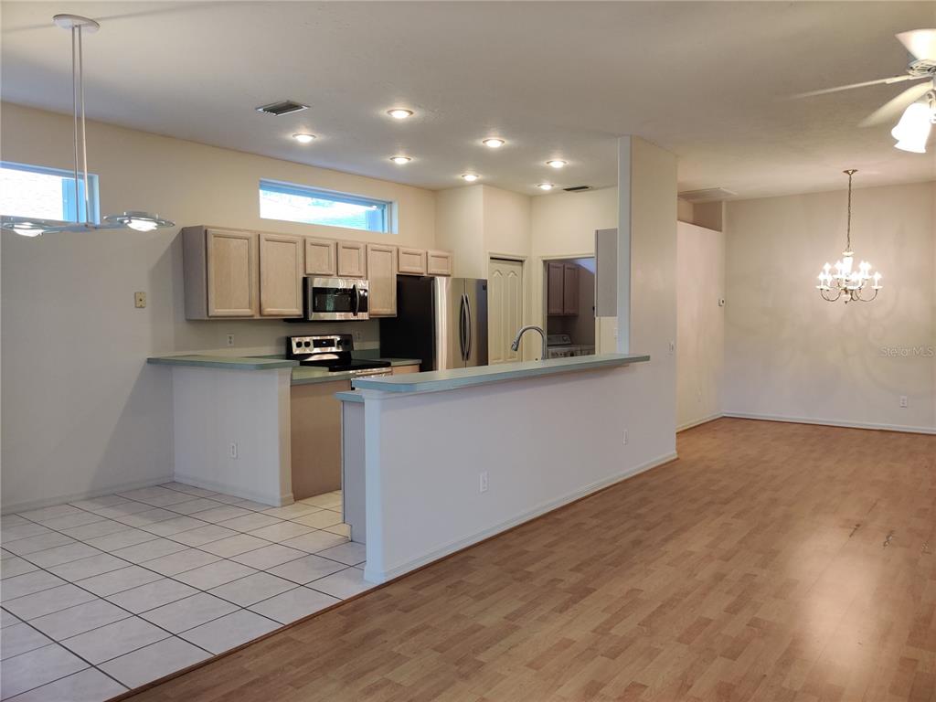 A kitchen with light wood cabinets and a breakfast bar overlooks a dining area — 4469 EDINBRIDGE CIRCLE UNIT 25, SARASOTA, FL