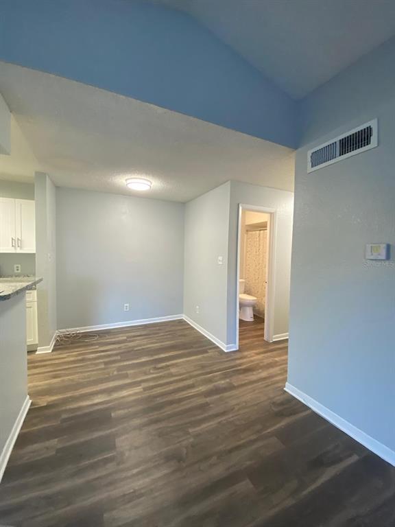 A room with light blue walls, wood-look flooring, and a doorway leading to a bathroom — 4400 THORNBRIAR LANE UNIT 205, ORLANDO, FL