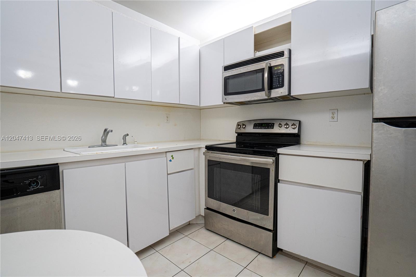 A kitchen features white cabinets, stainless steel appliances, and light-colored tile flooring — 600 Three Islands Blvd # 316, Hallandale Beach FL 33009, HALLANDALE BEACH, FL