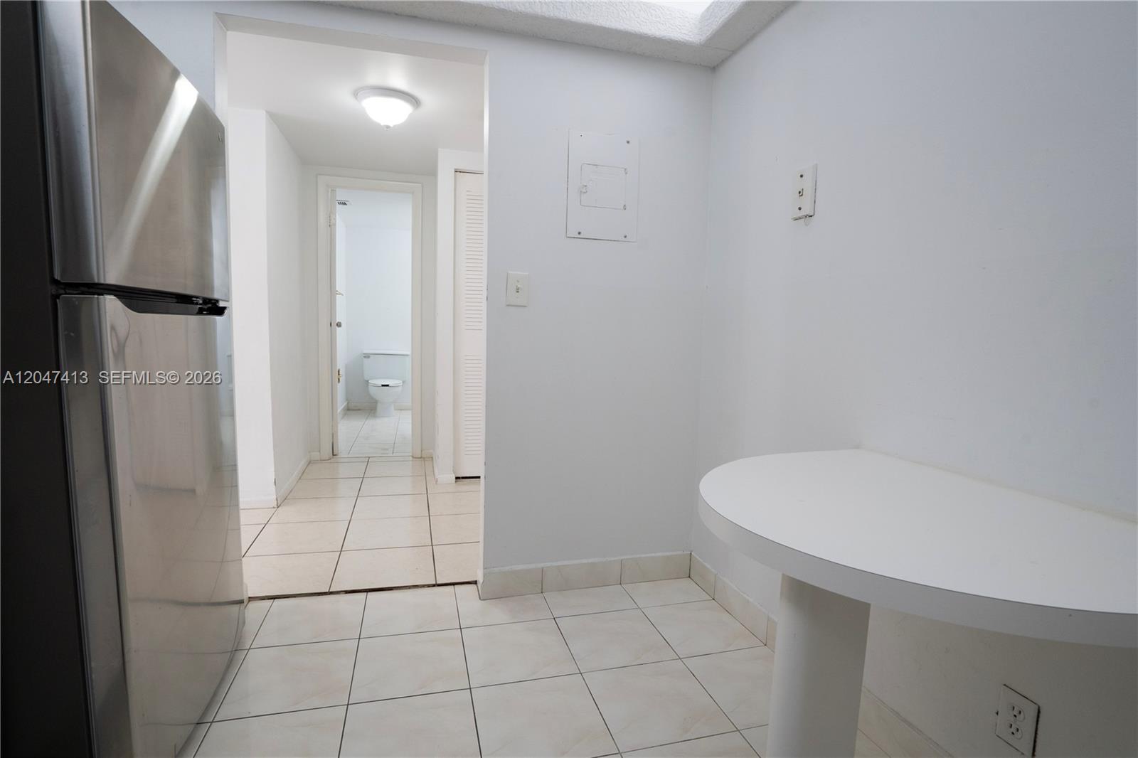 A kitchen area features a stainless steel refrigerator, white tile flooring, and a small table — 600 Three Islands Blvd # 316, Hallandale Beach FL 33009, HALLANDALE BEACH, FL