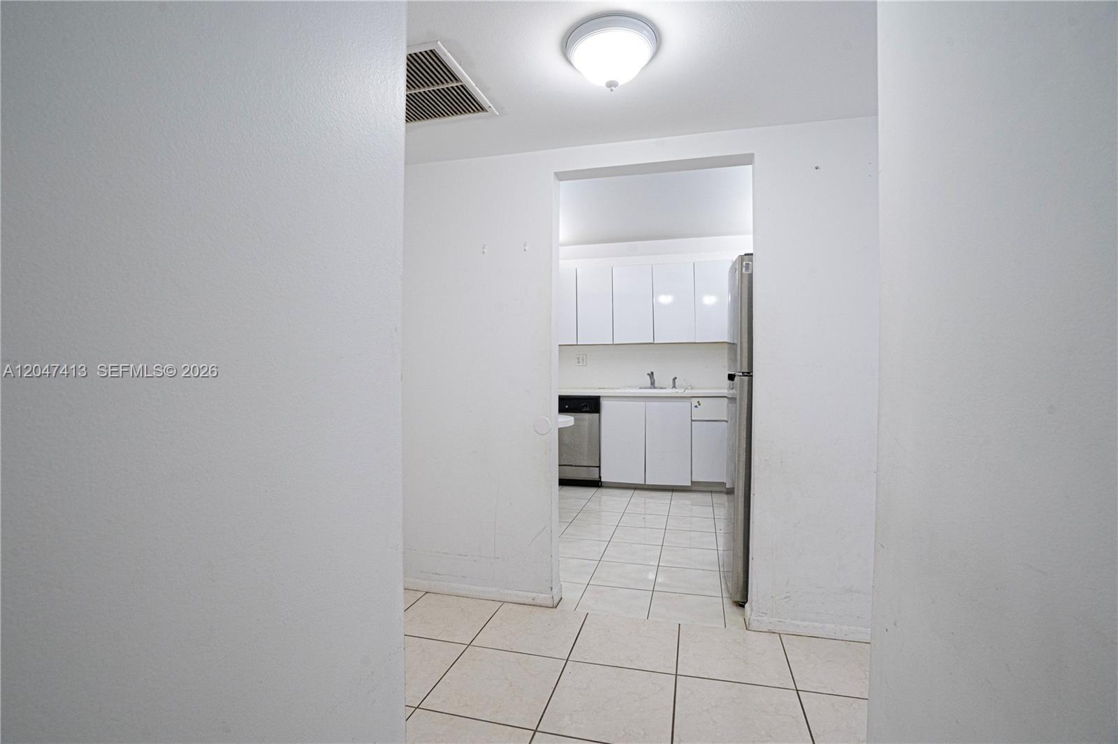 A view through a doorway shows a kitchen with white cabinets and tiled floors — 600 Three Islands Blvd # 316, Hallandale Beach FL 33009, HALLANDALE BEACH, FL