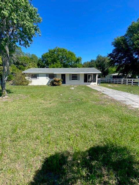 A single-story house with a light-colored exterior sits on a grassy lot under a clear sky — 4316 E KNIGHTS GRIFFIN ROAD, PLANT CITY, FL