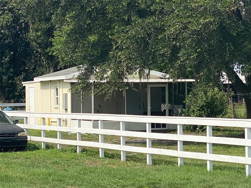 A light-colored house with a screened-in porch sits behind a white wooden fence — 4316 E KNIGHTS GRIFFIN ROAD, PLANT CITY, FL