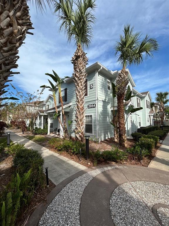 A light green multi-story building features palm trees and a sidewalk in the foreground — 2954 LUCAYAN HARBOUR CIRCLE UNIT 106, KISSIMMEE, FL