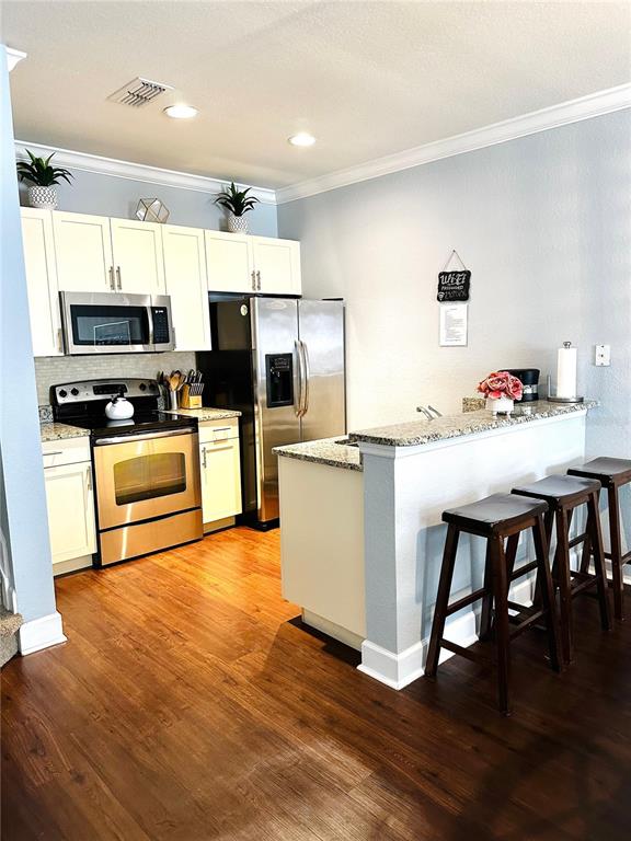 A kitchen features white cabinets, stainless steel appliances, granite countertops, and a breakfast bar — 2954 LUCAYAN HARBOUR CIRCLE UNIT 106, KISSIMMEE, FL