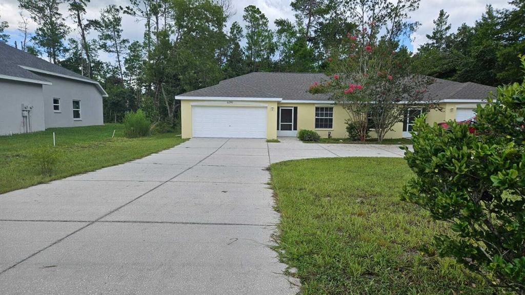 A single-story house with a yellow exterior, a two-car garage, and a concrete driveway — 6290 W OAK PARK BOULEVARD, HOMOSASSA, FL