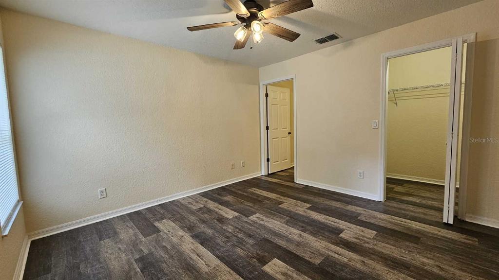 A bedroom features wood-look flooring, a ceiling fan, and doorways leading to a closet and hallway — 6290 W OAK PARK BOULEVARD, HOMOSASSA, FL