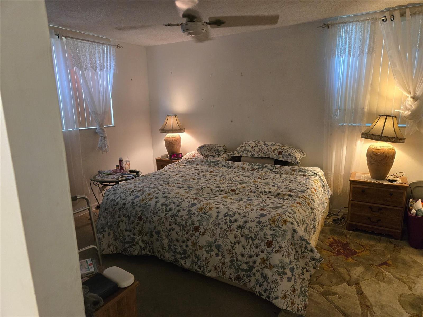 A bedroom features a floral bedspread, two matching lamps on nightstands, and two windows with curtains — 3080 Holiday Springs Boulevard # 209, Margate FL 33063, MARGATE, FL