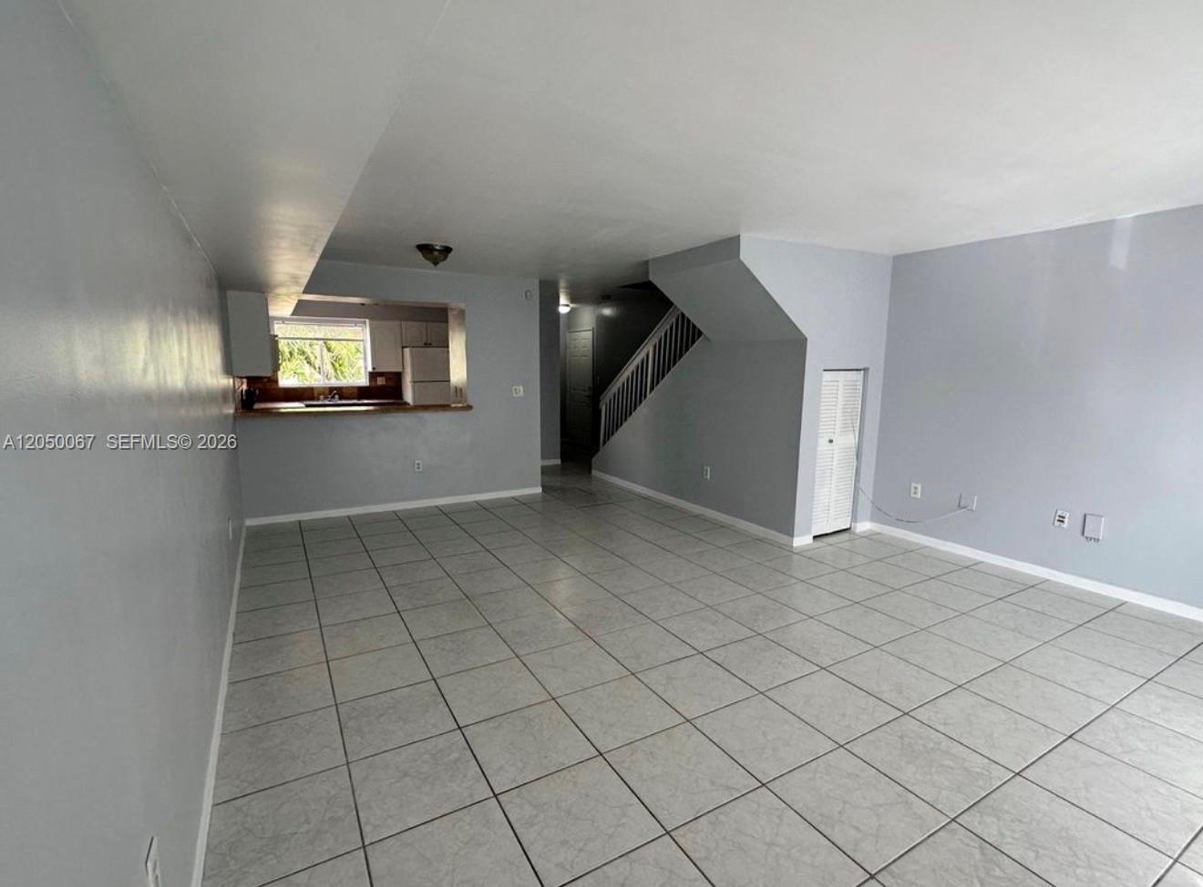 A living area with light gray walls, tiled floors, and a staircase leading upstairs — 14909 SW 80th St # 205, Miami FL 33193, MIAMI, FL