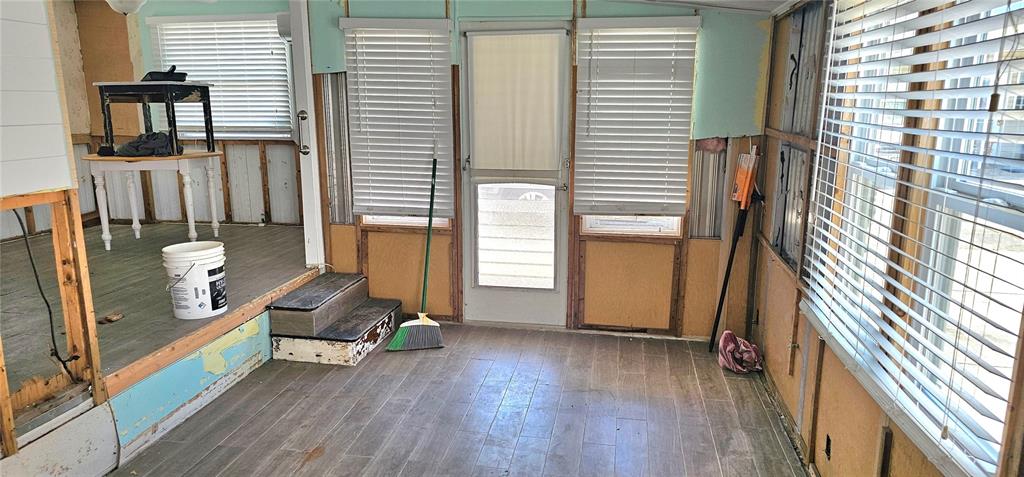 A sunroom under renovation features wood-look flooring, exposed wall studs, and a raised platform area — 41 2ND STREET, BRADENTON, FL