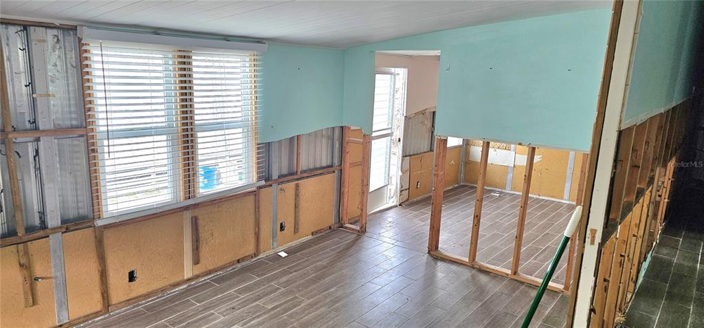 An unfinished room features exposed wall studs, light blue painted panels, and wood-look tile flooring — 41 2ND STREET, BRADENTON, FL