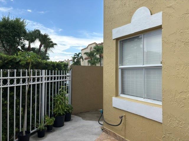 A view of a tan exterior wall with a window and a white metal fence — 415 NW 85th Pl # 1701, Miami FL 33126, MIAMI, FL