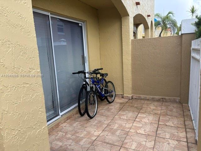 Two bicycles are parked on a tiled patio outside a sliding glass door — 415 NW 85th Pl # 1701, Miami FL 33126, MIAMI, FL