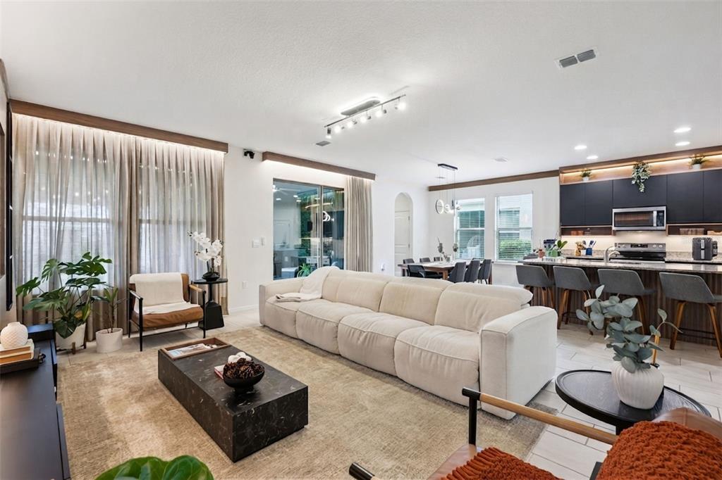 A bright open-concept living room features a large beige sofa, marble coffee table, and kitchen — 17070 WATER SPRING BOULEVARD, WINTER GARDEN, FL