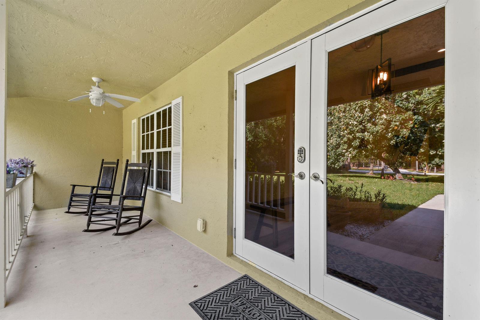 A covered porch features two rocking chairs, a ceiling fan, and double glass entry doors — 17861 Winterhawk Trail, FL 33478, FL