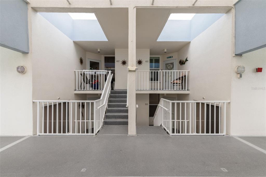 An exterior view of a multi-level apartment building featuring open walkways, staircases, and balconies — 5279 ISLA KEY BOULEVARD S UNIT 413, ST PETERSBURG, FL