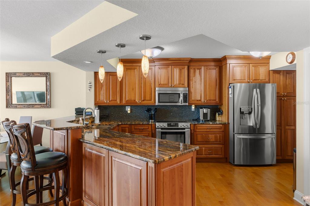 A kitchen features wood cabinets, granite countertops, stainless steel appliances, and a breakfast bar — 5279 ISLA KEY BOULEVARD S UNIT 413, ST PETERSBURG, FL