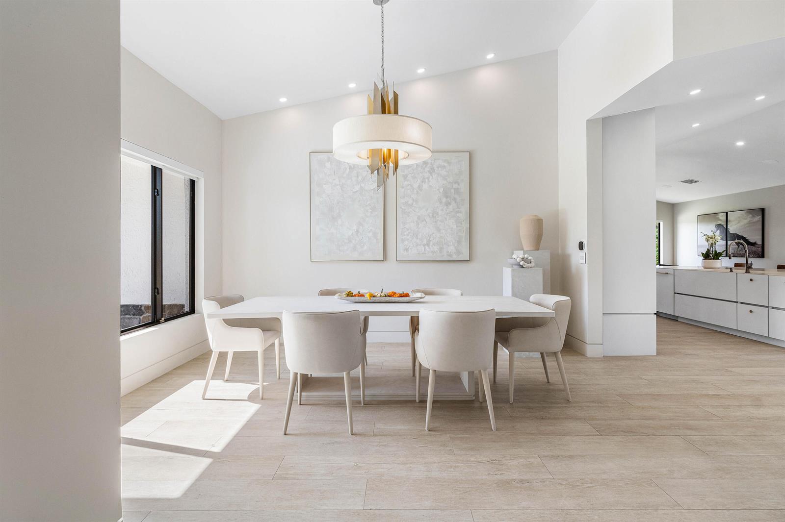 A modern dining room features a white table, upholstered chairs, and a gold pendant light — 11173 Manatee, Lake Worth FL 33449, LAKE WORTH, FL