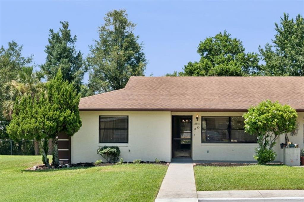 A single-story house with a beige exterior, a brown shingled roof, and a front walkway — 12441 ORANGEWOOD CIRCLE, TAVARES, FL