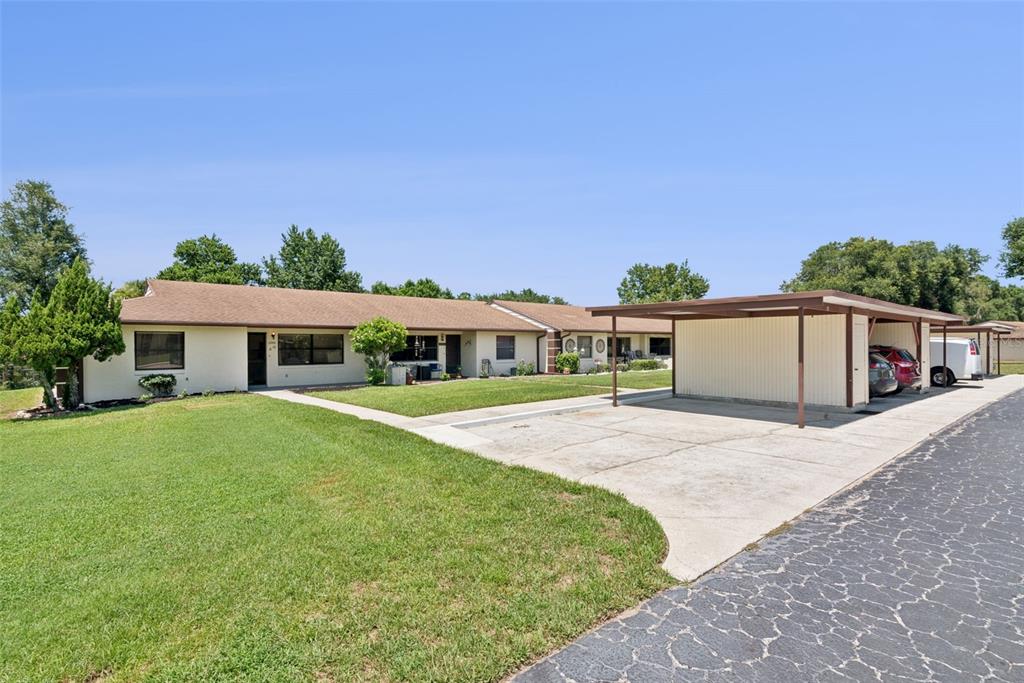 A single-story apartment building with a lawn and a covered carport area — 12441 ORANGEWOOD CIRCLE, TAVARES, FL