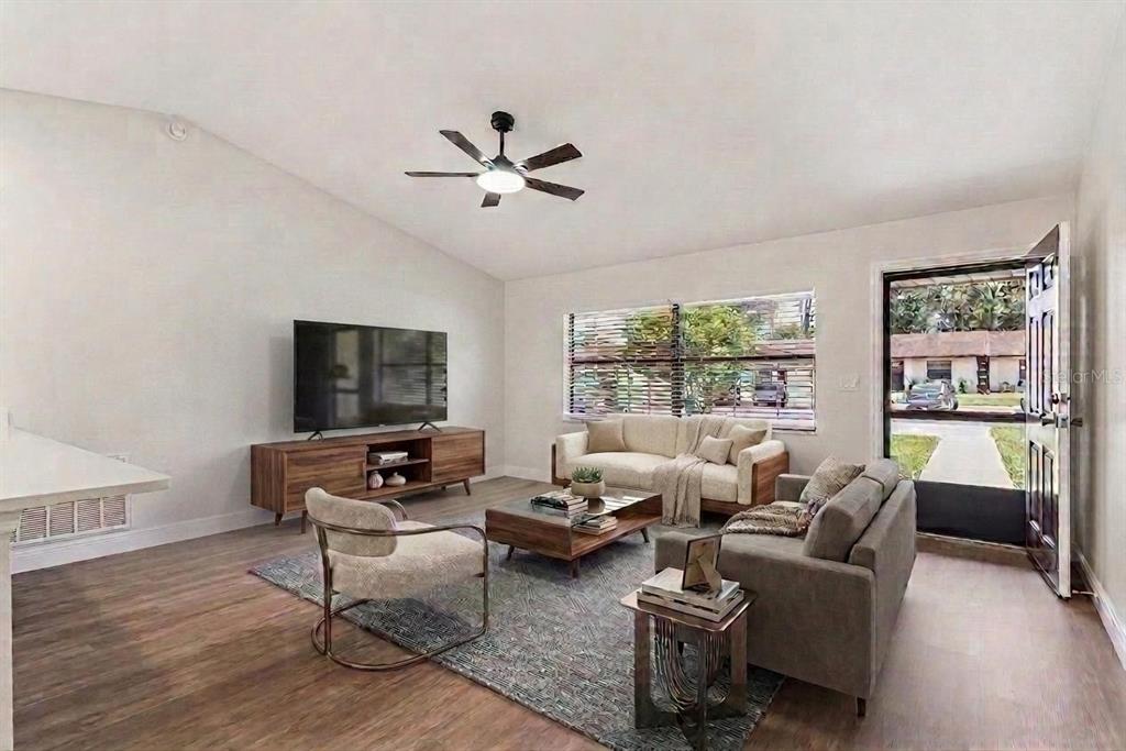 A living room with wood-look flooring, a ceiling fan, a large window, and an entryway — 12441 ORANGEWOOD CIRCLE, TAVARES, FL