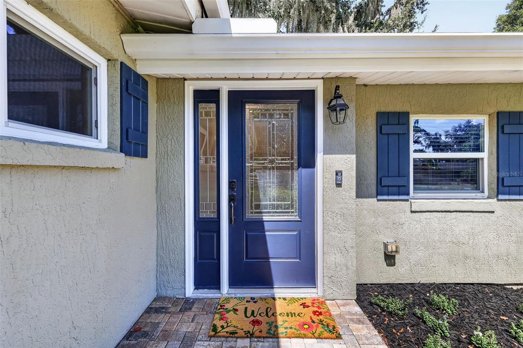 The exterior of a house features a blue front door, shutters, and a welcome mat — 2434 TRACE AVE, BELLE ISLE, FL