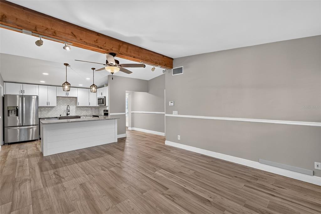 A kitchen with white cabinets and a breakfast bar opens into a living area — 2434 TRACE AVE, BELLE ISLE, FL