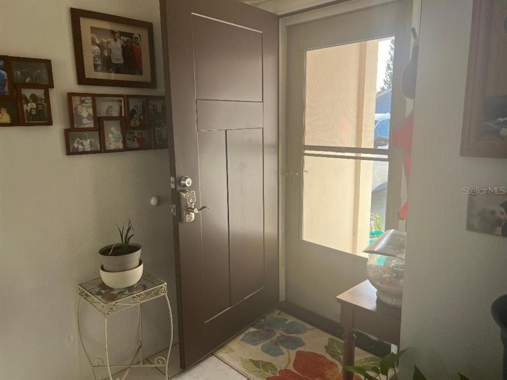 A brown front door opens into an entryway with a gallery wall of framed photos — 2009 SAN SEBASTIAN WAY S, CLEARWATER, FL