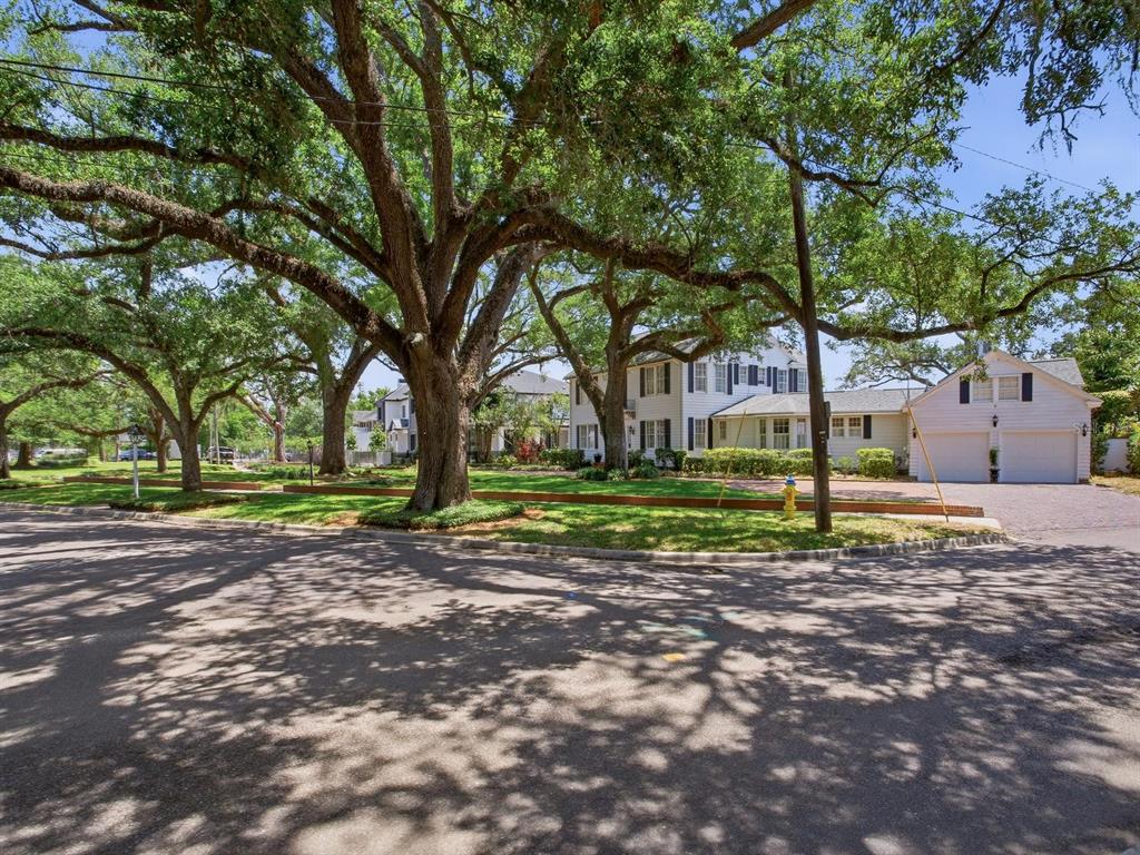 A white two-story house with a detached garage sits behind large oak trees — 3424 JEAN CIRCLE, TAMPA, FL