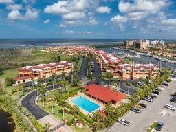 An aerial view shows a residential complex with swimming pools, parking lots, and a nearby marina — 3220 SOUTHSHORE DRIVE UNIT 22C, PUNTA GORDA, FL