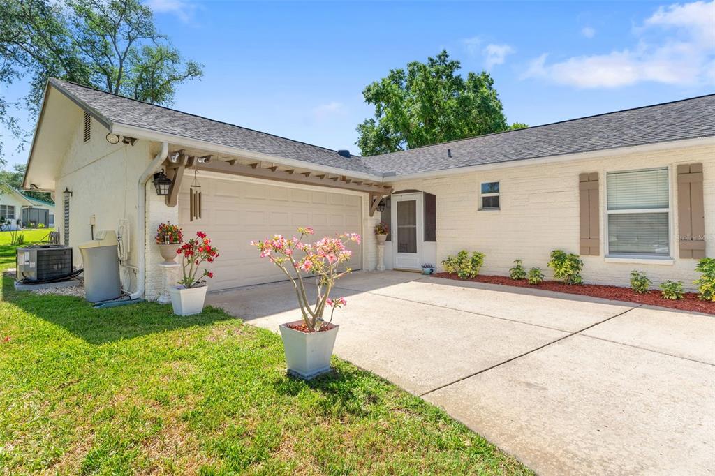 A single-story house with a white brick exterior, a two-car garage, and a concrete driveway — 10520 SPRINGWOOD DRIVE, PORT RICHEY, FL