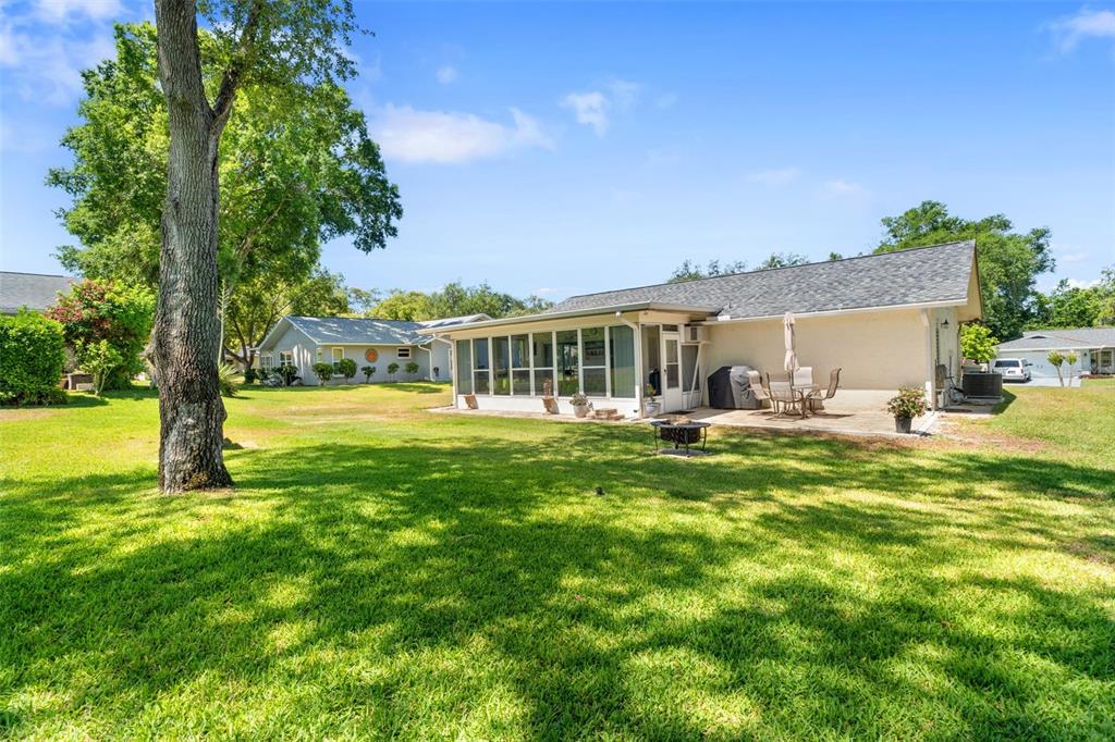The exterior of a house features a screened-in porch, a patio, and a large lawn — 10520 SPRINGWOOD DRIVE, PORT RICHEY, FL